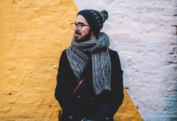 homme contre un mur porte echarpe et bonnet