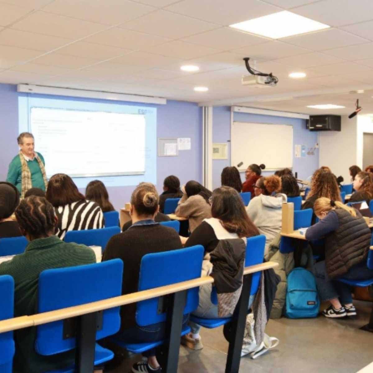 Une classe d'élèves de dos face à un professeur 