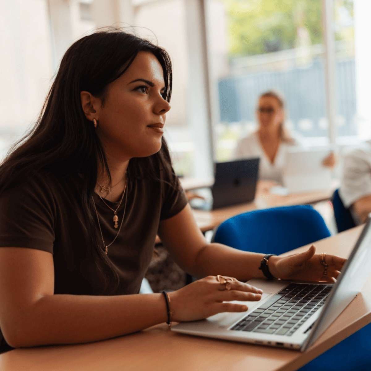 Jeune femme brune étudiante en classe devant son ordinateur