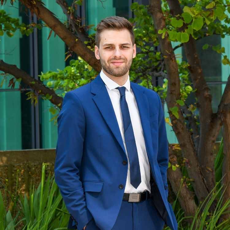 Jeune homme blond en costume dehors